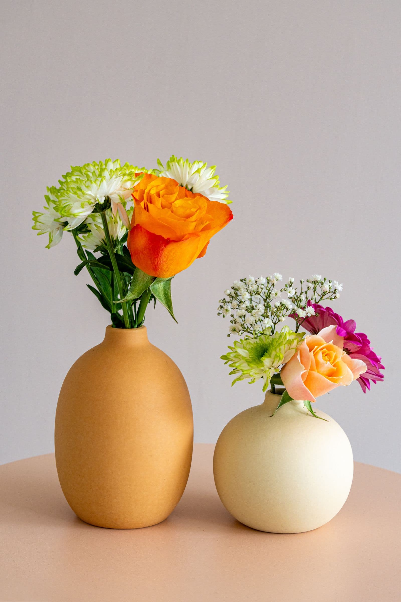 Dos floreros de cerámica con flores frescas sobre una mesa