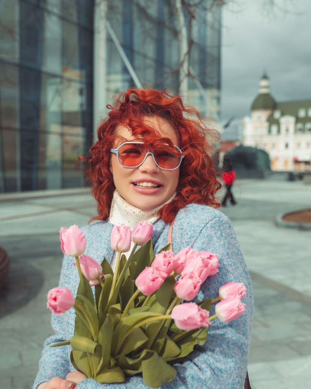 Mujer en la calle recibiendo un ramo de tulipanes rosas